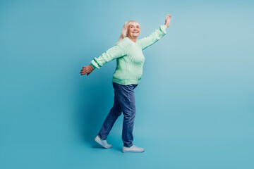 Candid old woman walk raise hands isolated over blue background