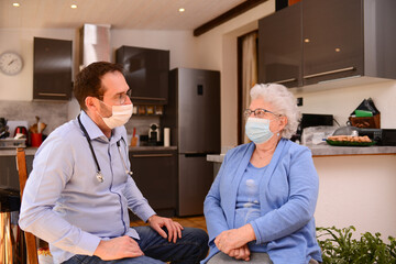 Obraz premium young male doctor checking medical exam consultation to an elderly senior woman at home wearing surgical mask to avoid covid 19 contamination