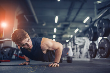 Fototapeta na wymiar Young athletic man doing push-ups in gym. Muscular and strong gu