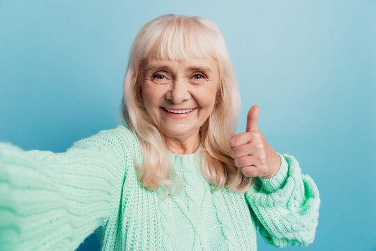 Happy cheerful mature lady taking selfie show fine thumbup sign isolated on blue background