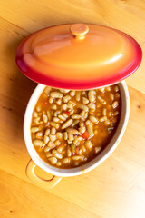 Guiso de almejas y judías asturianas servido en un cuenco de naranja. Cocina española. Enfoque selectivo. Fabes con marisco.