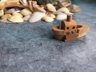 Toy boat made of wood against the background of seashells on a blue background. concept sea travel