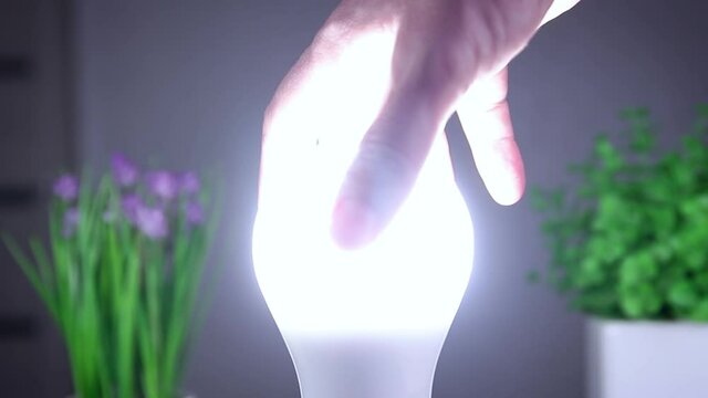 Man Rotates with His Hand a Led Bulb in Its Electrical Socket. Energy-saving, eco-friendly Led bulb lamp lights up