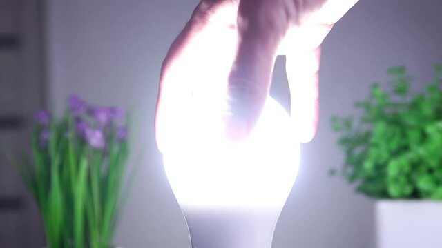 Man Rotates with His Hand a Led Bulb in Its Electrical Socket. Energy-saving concept.