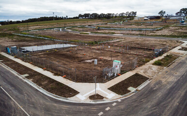 Aerial views on a newly created Australian housing estate. Construction starts on a newly titled block of land, construction fences are up and within months a new house will be built on this site. - obrazy, fototapety, plakaty
