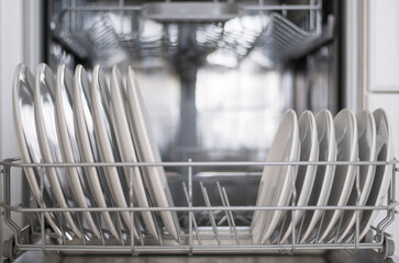 White flat plates are loaded into the dishwasher