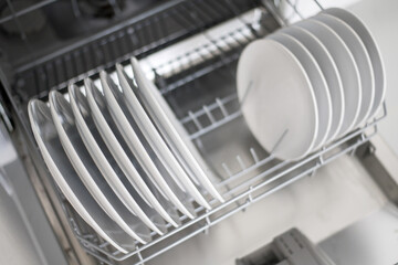 Obraz na płótnie Canvas White flat plates are loaded into the dishwasher