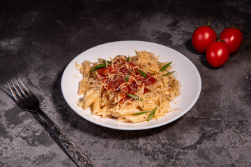 Penne pasta with tomatoes, sauce, cheese and Provencal herbs. Dark background. Space for copying. Top view. Penne pasta in tomato sauce - Italian food style