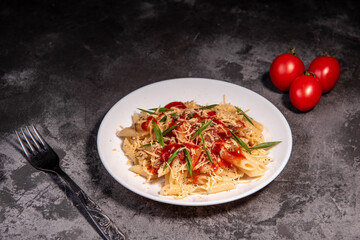 Penne pasta with tomatoes, sauce, cheese and Provencal herbs. Dark background. Space for copying. Top view. Penne pasta in tomato sauce - Italian food style