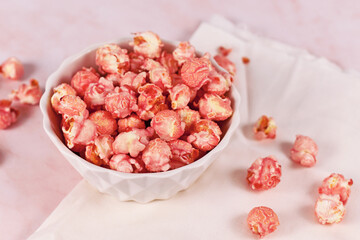 Fototapeta na wymiar Pink colored strawberry flavored sweet popcorn in white bowl
