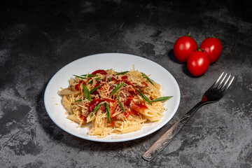 Penne pasta with tomatoes, sauce, cheese and Provencal herbs. Dark background. Space for copying. Top view. Penne pasta in tomato sauce - Italian food style