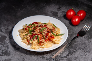 Penne pasta with tomatoes, sauce, cheese and Provencal herbs. Dark background. Space for copying. Top view. Penne pasta in tomato sauce - Italian food style