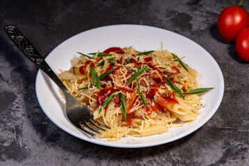 Penne pasta with tomatoes, sauce, cheese and Provencal herbs. Dark background. Space for copying. Top view. Penne pasta in tomato sauce - Italian food style