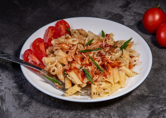 Penne pasta with tomatoes, sauce, cheese and Provencal herbs. Dark background. Space for copying. Top view. Penne pasta in tomato sauce - Italian food style