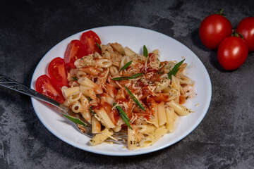 Penne pasta with tomatoes, sauce, cheese and Provencal herbs. Dark background. Space for copying. Top view. Penne pasta in tomato sauce - Italian food style