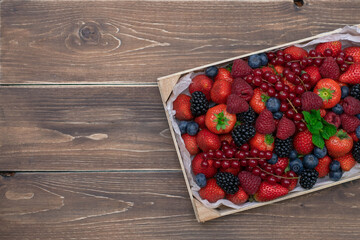 Wooden box with fresh berries on wooden vintage table.