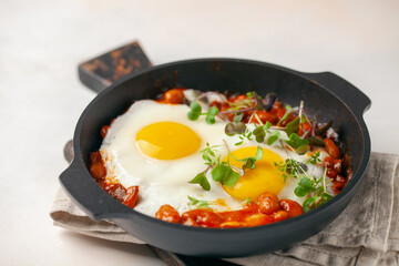 Continental breakfast - fried eggs and beans in tomato sauce in a serving pan on the table