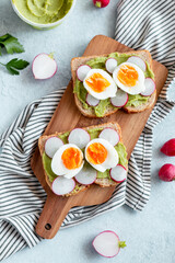 Healthy avocado and egg toasts for breakfast on board, top view, natural lighting