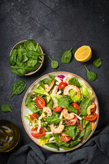 Shrimp salad with green leaves at stone table.
