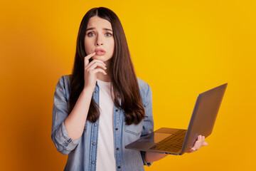 Portrait of girl with laptop finger chin nervous on yellow background