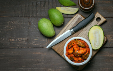 natural and homemade mango pickle or aam ka aachar on a rustic wooden background theme 