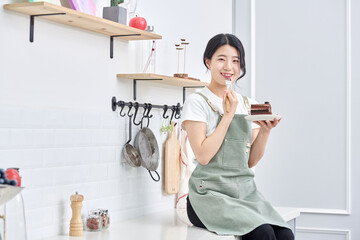 Asia Korean young woman serving a piece of chocolate cake on a plate