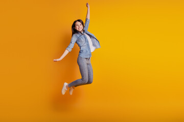 Fototapeta na wymiar Portrait of astonished girl jumping raise hand isolated on yellow background