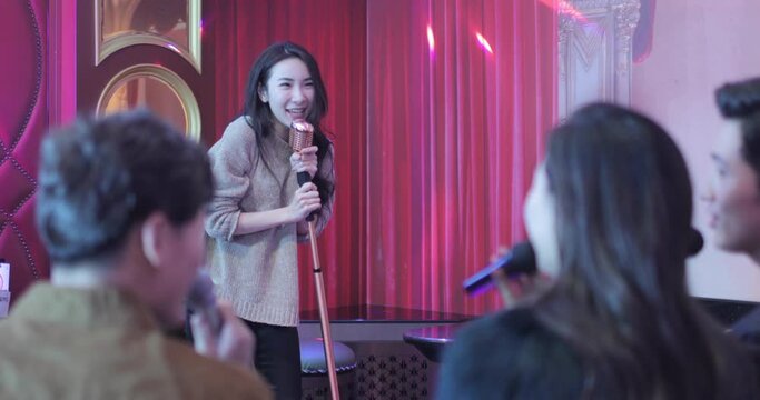Happy young friends singing karaoke in nightclub,4K