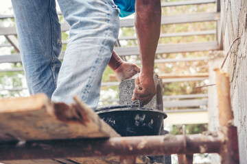 Closeup hands of the workers were plastering cement concrete on the walls with trowel at house construction site.
