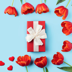 Mother's day background. Top view of gift with red tulip bouquet on blue table background