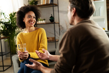 Young couple sitting and talking at home. Woman and man flirting and laughing