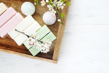 SPA soap backround. Aromatic natural soap with sakura flowers and bath bomb on a wooden background, top view