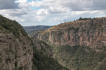 Fototapeta na wymiar Steep Rocky Cliffs Leading Down into a Tree Lined Gorge
