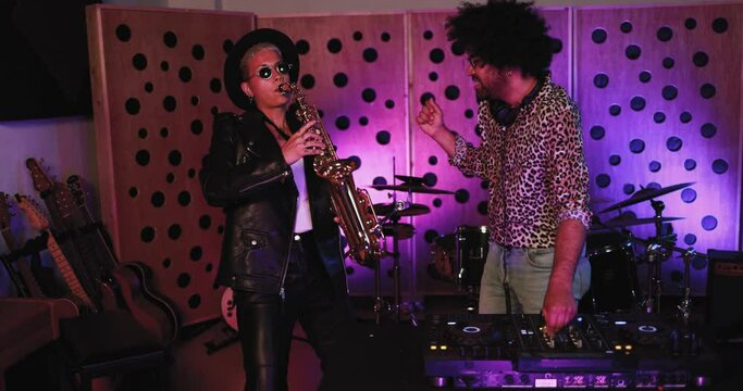 Young people dancing while record music inside a recording studio - Band, saxophone player and dj concept