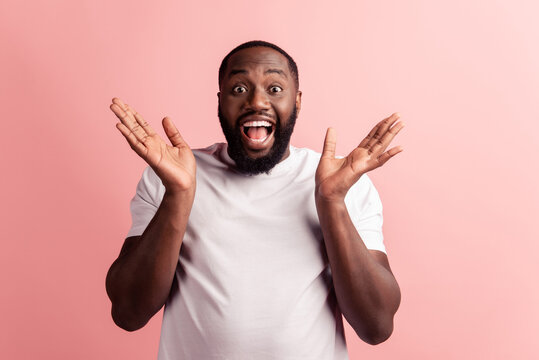 Photo of funny crazy amazed man raise hands open mouth on pink background