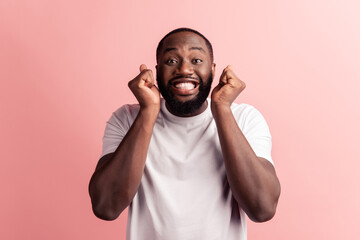 Fototapeta premium Photo of winner man hold fists toothy smile on pink background