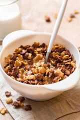 Tasty and healthy breakfast. Chocolate and vanilla cornflakes with milk in a white bowl close-up. Breakfast cereals.