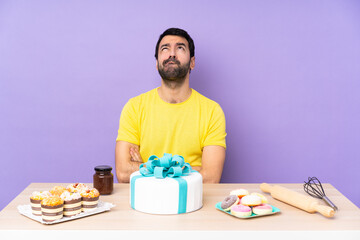 Man in a table with a big cake and looking up