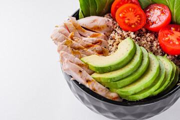 bowl of healthy quinoa with grilled chicken and vegetables on a white background