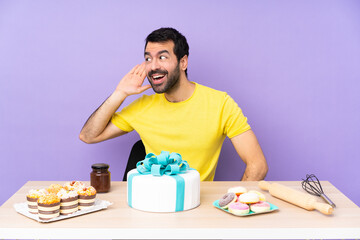 Man in a table with a big cake listening to something by putting hand on the ear