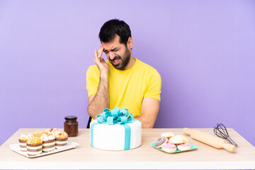 Man in a table with a big cake with headache