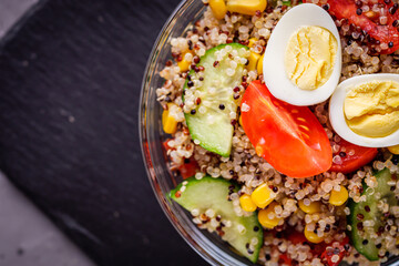 bowl of healthy quinoa with vegetables on a dark rustic background