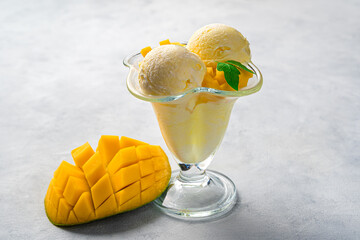 Creamy mango ice cream and fresh mango on a gray background.