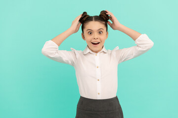 Surprised primary school girl child touch styled hair buns blue background, hairstyle