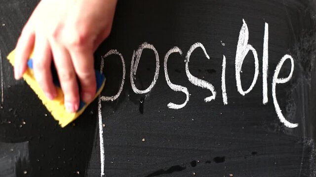 a woman's hand erases im and get an inscription possible instead of impossible on a chalk board