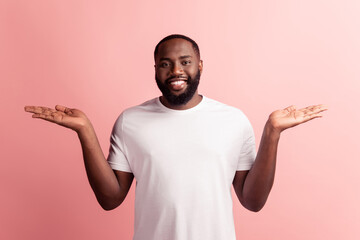 Portrait of promoter young manhands hold empty space on pink background