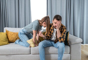 Young married couple is arguing over money because the shopaholic woman spent a lot of money from a credit card on online shopping and they did not pay the bills or the rent - obrazy, fototapety, plakaty