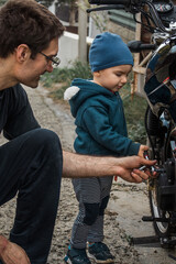 Father and son repair a motorcycle on the street. Dad and son at work. Communication between father and son.