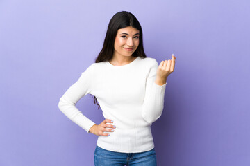 Young brunette woman over isolated purple background making Italian gesture