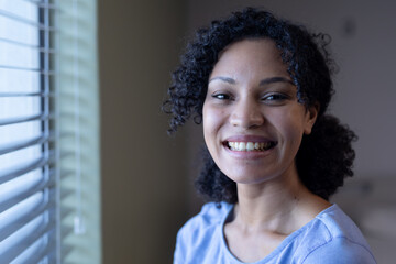 Portrait of mixed race female patient by window looking to camera and smiling